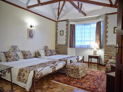 a bedroom with a bed and a couch and a window at The Drexel House Kenya in Nairobi