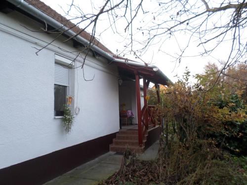 ein weißes Haus mit einer roten Veranda und einer Treppe in der Unterkunft Kerékpáros és Zarándok Vendégház in Apostag