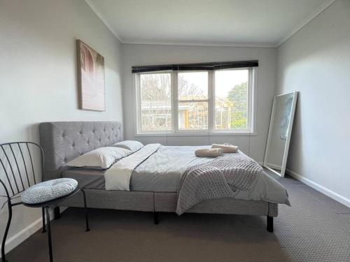 um quarto com uma cama com uma janela e uma cadeira em Charming House; Walk to Beach & Shops em Rosebud