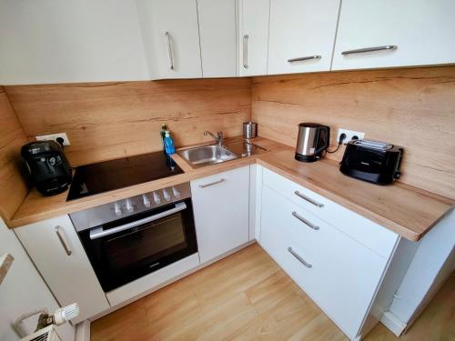a small kitchen with white cabinets and a sink at YourFavoriteBed Designwohnung Nähe Zentrum und Klinikum in Plauen