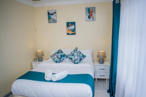 a bedroom with a bed with blue and white sheets and pillows at Arabella Suites - Karen in Karen