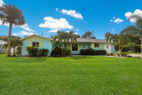ein grünes Haus mit Palmen im Hof in der Unterkunft Lazy Pelican home in Holmes Beach