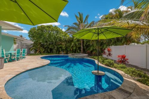 einen Pool mit einem grünen Sonnenschirm und Stühlen in der Unterkunft Lazy Pelican home in Holmes Beach