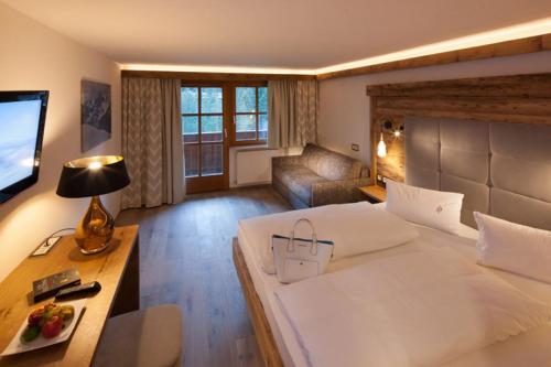 a hotel room with a large bed and a television at Alpine Lifestyle Berghotel Madlener in Damuls
