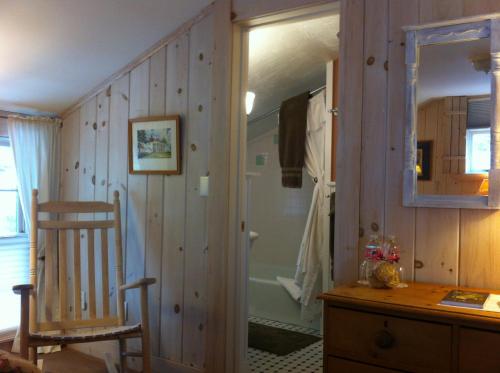 a bathroom with a mirror and a wooden wall at Deerhill Inn in West Dover