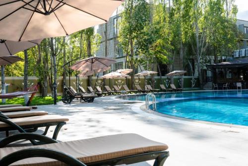 una piscina con sillas y sombrillas junto a un edificio en VOGUE HOTEL RESORT AND SPA - Nabran, en Nabran