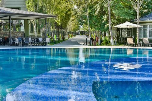 a blue swimming pool with chairs and an umbrella at VOGUE HOTEL RESORT AND SPA - Nabran in Nabran