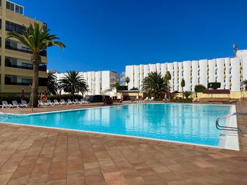 a large swimming pool with palm trees and buildings at Excelsior I Sea View Apartment in Maspalomas