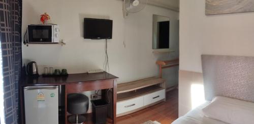 a small room with a bed and a tv on the wall at NB House in Karon Beach