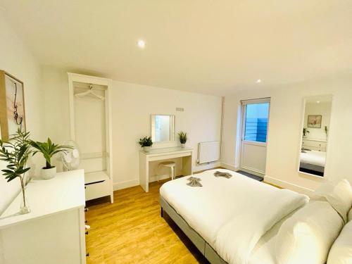 a white bedroom with a large bed and a couch at Prosper House Apartments in Norwich