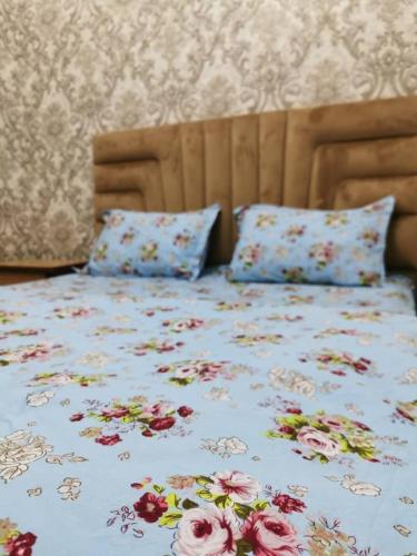 uma cama com flores com duas almofadas em Aisha em Bishkek