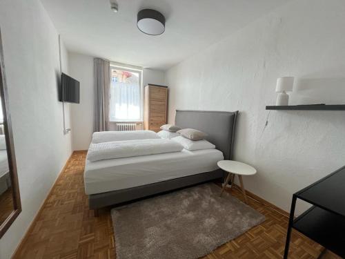 a white bedroom with a bed and a table at Gasthof - Auszeit im Bad Diezlings - Adults only in Hörbranz