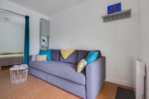 ein Wohnzimmer mit einer blauen Couch mit Kissen in der Unterkunft Le Loriot in Saint-Nic