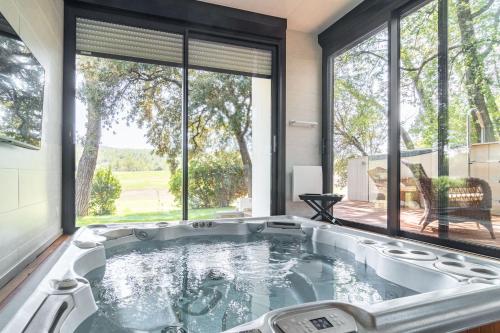 une baignoire jacuzzi dans une chambre avec de grandes fenêtres dans l'établissement Villa DaoL - Villa avec piscine et jacuzzi, à Flassans-sur-Issole