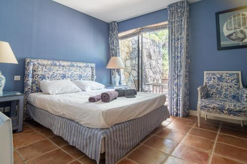 Schlafzimmer mit einem Bett mit blauen Wänden und einem Fenster in der Unterkunft Villa DaoL - Villa avec piscine et jacuzzi in Flassans-sur-Issole