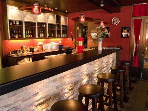 um bar com bancos num restaurante com paredes vermelhas em Hotelli Haapakannel em Haapavesi