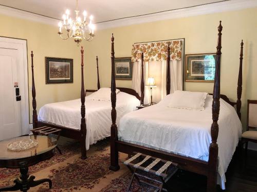 een slaapkamer met 2 bedden en een kroonluchter bij Belmont Inn in Shelbyville