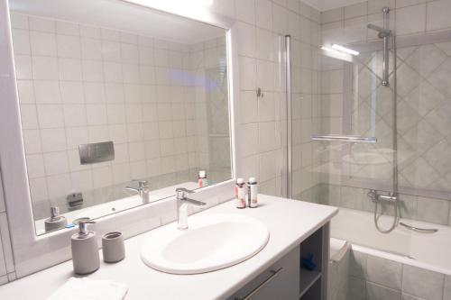a bathroom with a sink and a shower with a mirror at Crete Garden Guesthouse in Agios Nikolaos