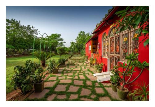 a stone path next to a red building with plants at An Authentic Village Farm in Jhānsi