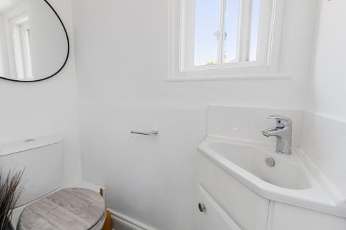 een witte badkamer met een wastafel en een spiegel bij River Exe Cottage waterfront in Exeter