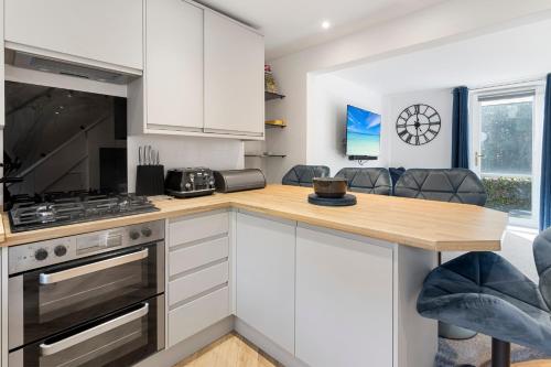 a kitchen with white cabinets and a wooden counter top at River Exe Cottage waterfront in Exeter