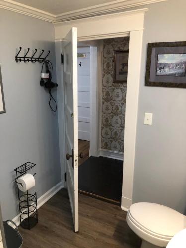 a bathroom with a white toilet and a hallway at Belmont Inn in Shelbyville