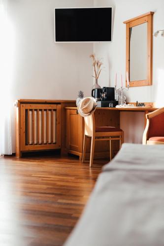 a room with a bed and a desk with a television at Das Stadthaus in Neusiedl am See