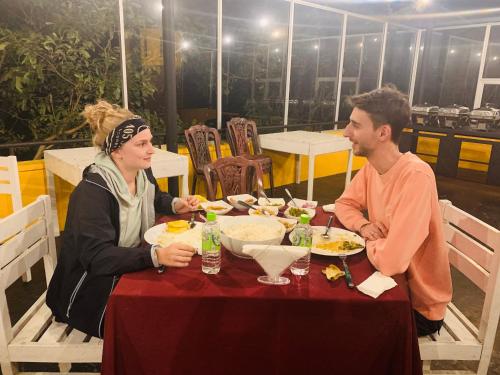 mężczyzna i kobieta siedzący przy stole jedzący jedzenie w obiekcie Sethway Village w mieście Minneriya