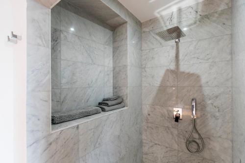 a bathroom with a shower with white marble walls at Valletta Collection - 101 Republic in Valletta