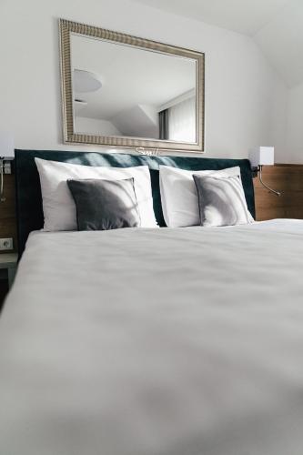 a bedroom with a large white bed with a mirror at Das Stadthaus in Neusiedl am See