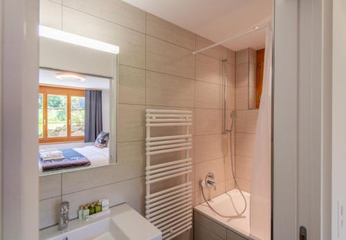a bathroom with a sink and a shower and a mirror at Panoramapark Soleil B Garden Apartment in Wengen