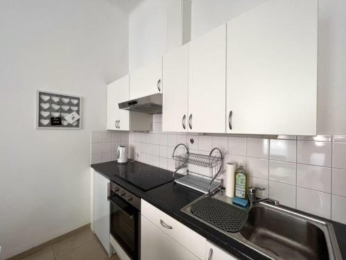 a kitchen with white cabinets and a sink at City-Apartment in Wieden in Vienna