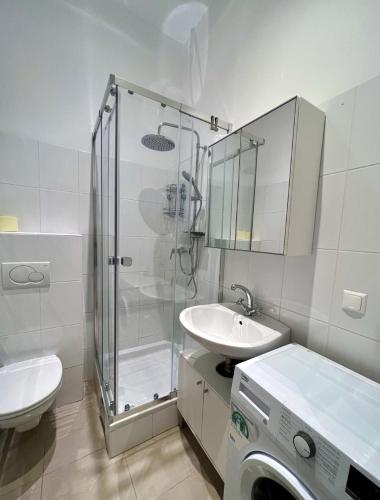 a bathroom with a shower and a sink and a washing machine at City-Apartment in Wieden in Vienna