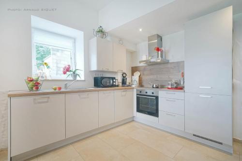 a white kitchen with white cabinets and a window at Gîte familial ferme des aujes falaen in Onhaye
