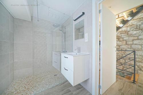 La salle de bains blanche est pourvue d'un lavabo et d'une douche. dans l'établissement Gîte familial ferme des aujes falaen, à Onhaye