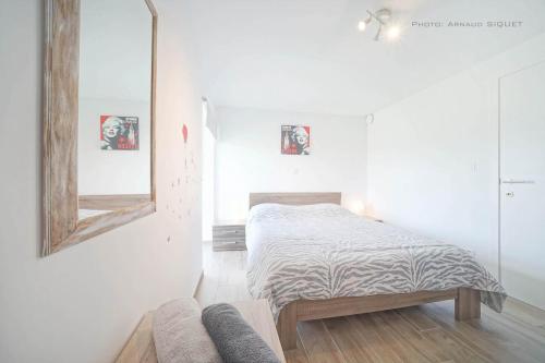 - une chambre blanche avec un lit et un miroir dans l'établissement Gîte familial ferme des aujes falaen, à Onhaye