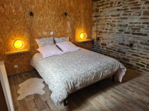 a bedroom with a bed with two lights on the wall at Gîte de L'Hotel Mahey in Champrépus