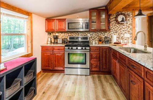 a kitchen with wooden cabinets and a stove top oven at The Nook Lodge - cabin with hot tub at Shawnee and Camelback Mtn in East Stroudsburg