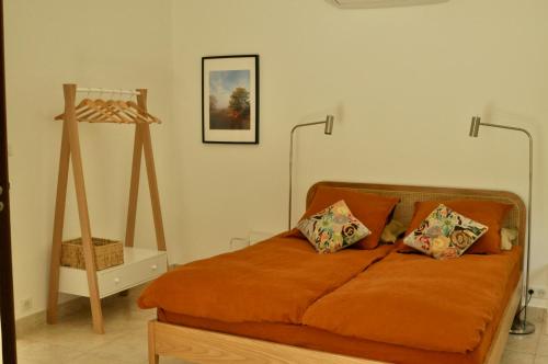 een slaapkamer met een bed met oranje lakens en 2 kussens bij Le Jardin de Fresnes in Fresnes-en-Woëvre