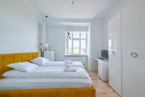 a white bedroom with a large bed and a desk at Dom & House - Apartment Golden Loft Sopot in Sopot