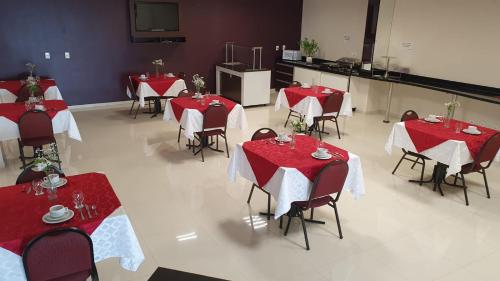 LH Plaza Hotel في تشابيكو: غرفة طعام مع طاولات وكراسي حمراء وبيضاء