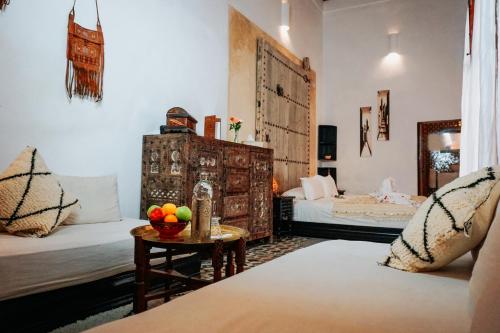 Habitación con 2 camas y mesa con fruta. en Riad Nora, en Marrakech