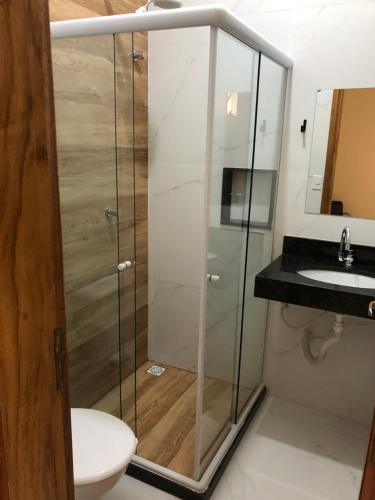 a shower with a sink and a toilet in a bathroom at Pousada Escotilha in Arraial do Cabo