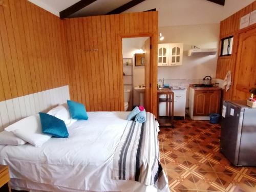 1 dormitorio con cama blanca y almohadas azules en Tuava Lodge, en Hanga Roa