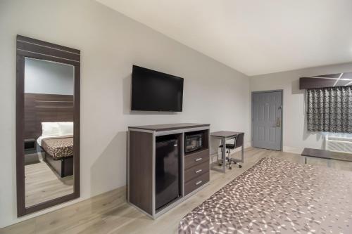 a bedroom with a bed and a tv on a wall at Americas Best Value Platinum Inn & Suites in Houston