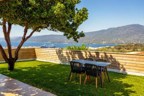 a table and chairs on a lawn with a view of the water at Résidence U Frusteru in Propriano