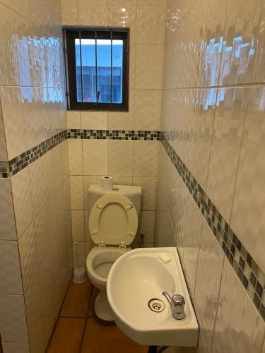 a bathroom with a toilet and a sink and a window at Soweto Towers Guest Accommodation in Soweto