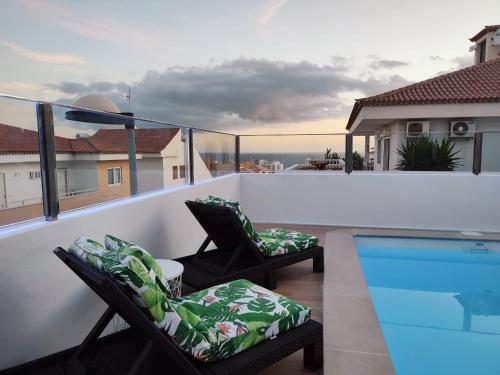 einen Balkon mit 2 Stühlen und einem Pool in der Unterkunft Fantástica Villa Cusmano con piscina privada in Adeje
