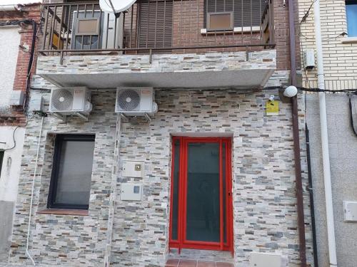 ein Backsteingebäude mit einer roten Tür und einem Fenster in der Unterkunft piso acogedor con encanto in Navas del Rey
