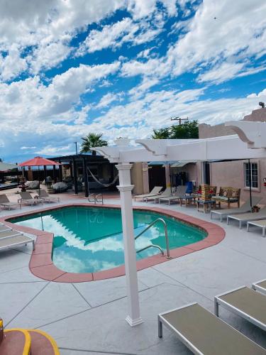 a pool at a resort with tables and chairs at MI KASA HOT SPRINGS 420,Adults Only, Clothing Optional in Desert Hot Springs